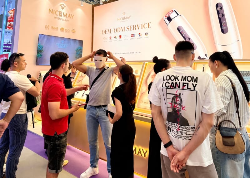 Visitors speaking with the NICEMAY team at an OEM and ODM beauty device exhibition booth in Shanghai.
