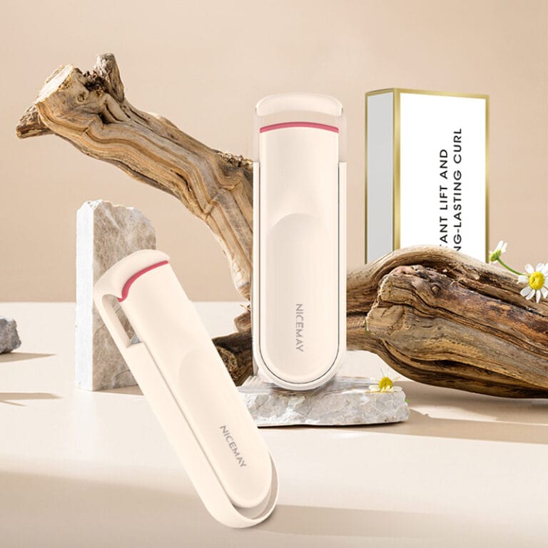 Nicemay warm ivory electric heated eyelash curler with rose pink accent displayed on a premium beige beauty set.